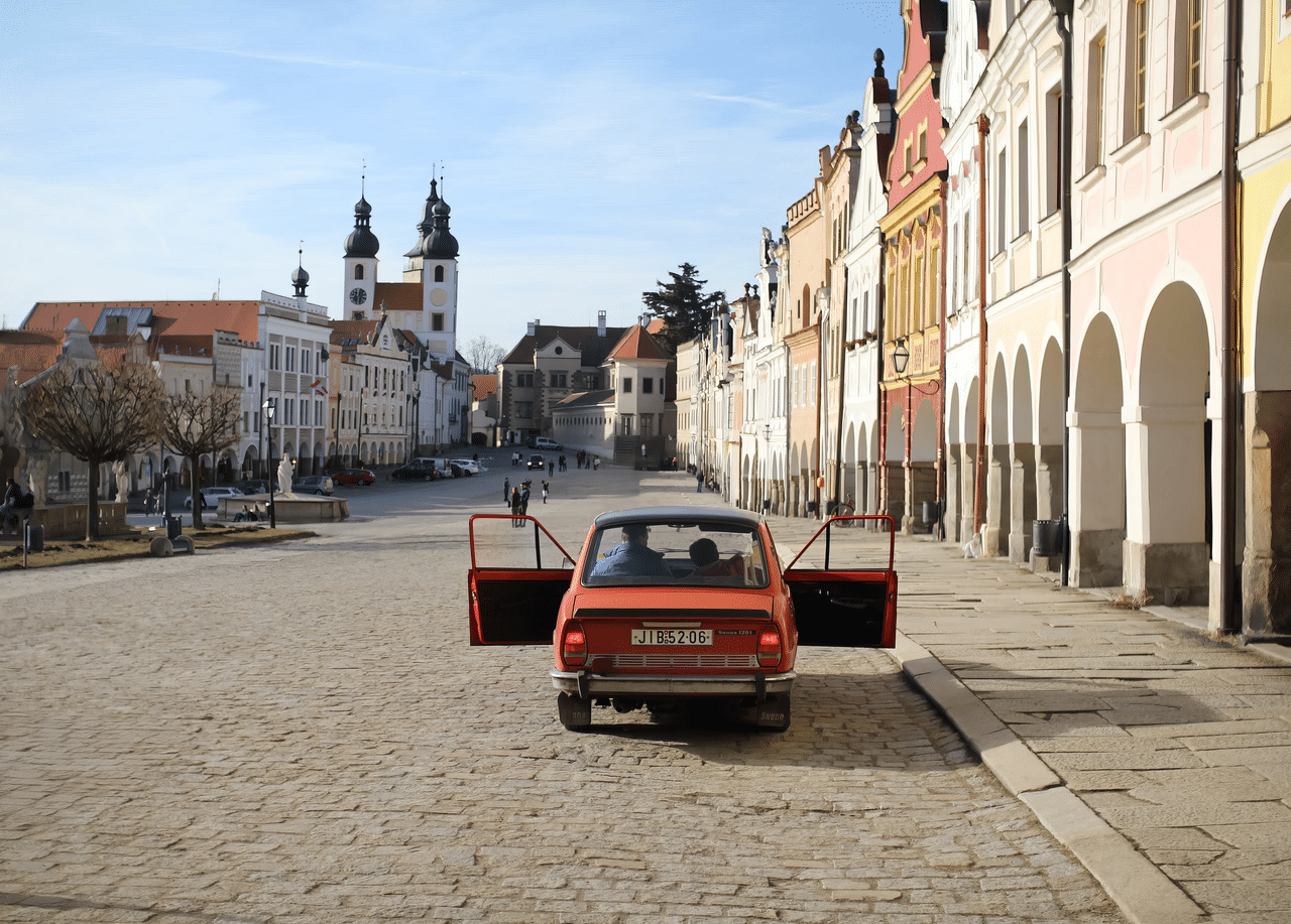 Vintage car parked in a picturesque historic square with open doors in Czechia.